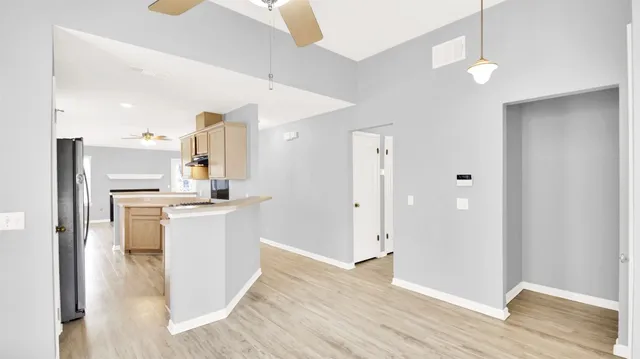 a view of kitchen with refrigerator cabinets and wooden floor