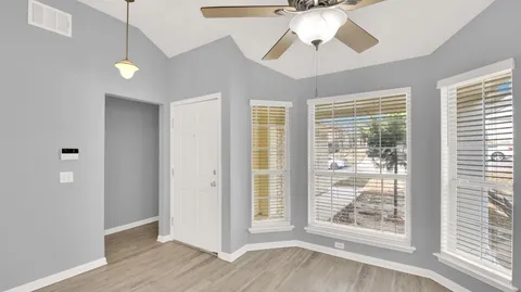 a view of an empty room with a window and wooden floor