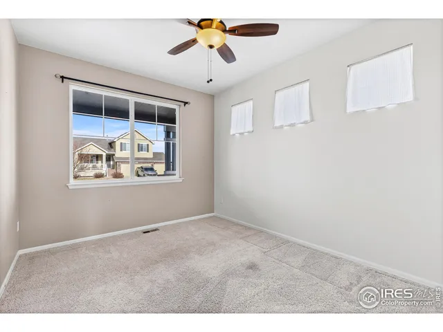 an empty room with windows and ceiling fan