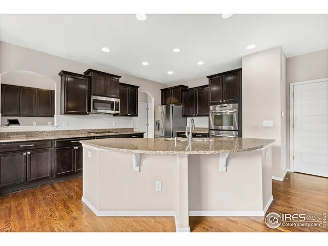 a kitchen with stainless steel appliances granite countertop a sink a stove top oven a counter space and cabinets