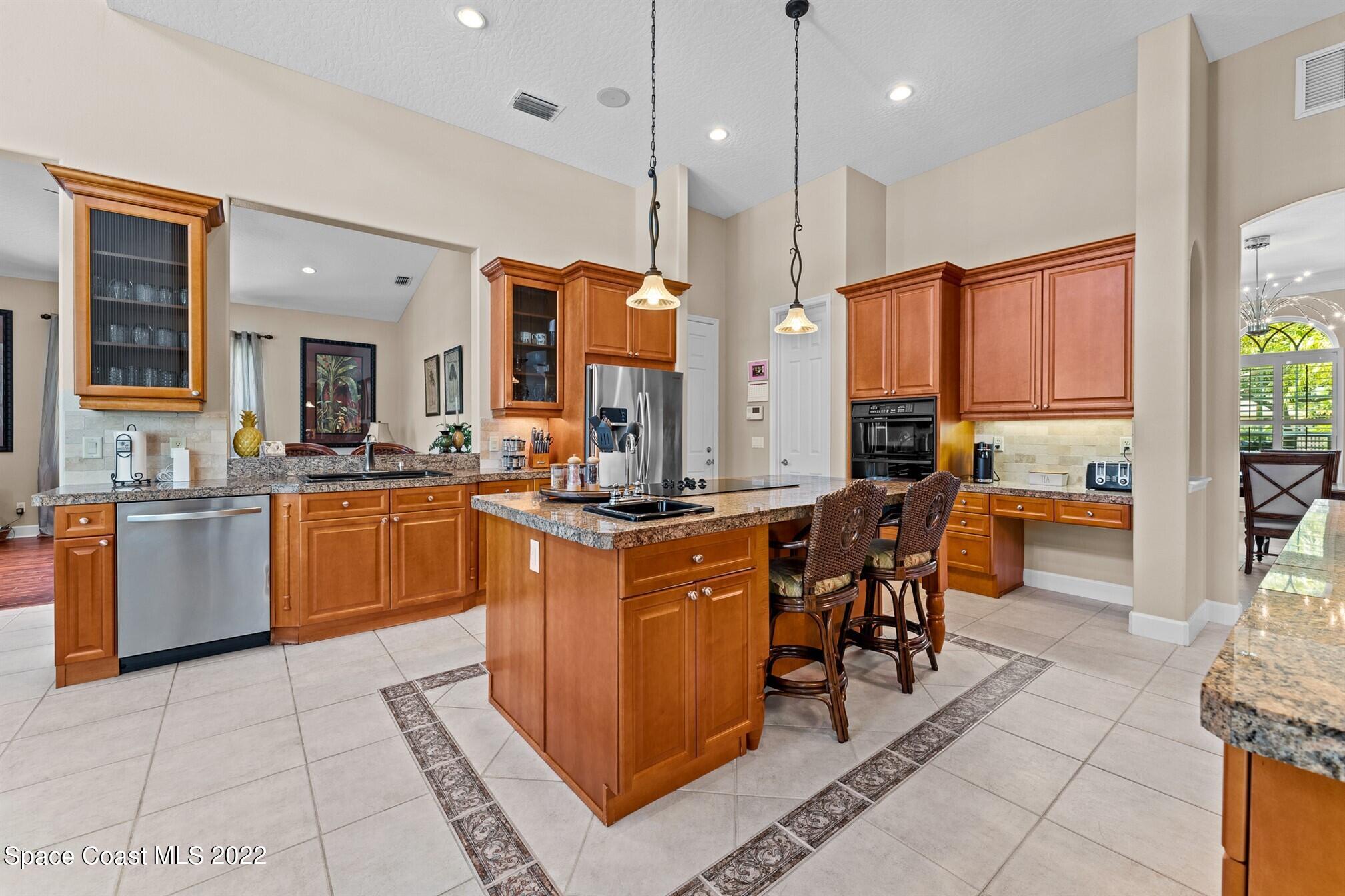 581 Nightingale Drive Indialantic, FL 32903 - Photo 17 of 67 a kitchen with stainless steel appliances kitchen island granite countertop a stove a sink and a refrigerator