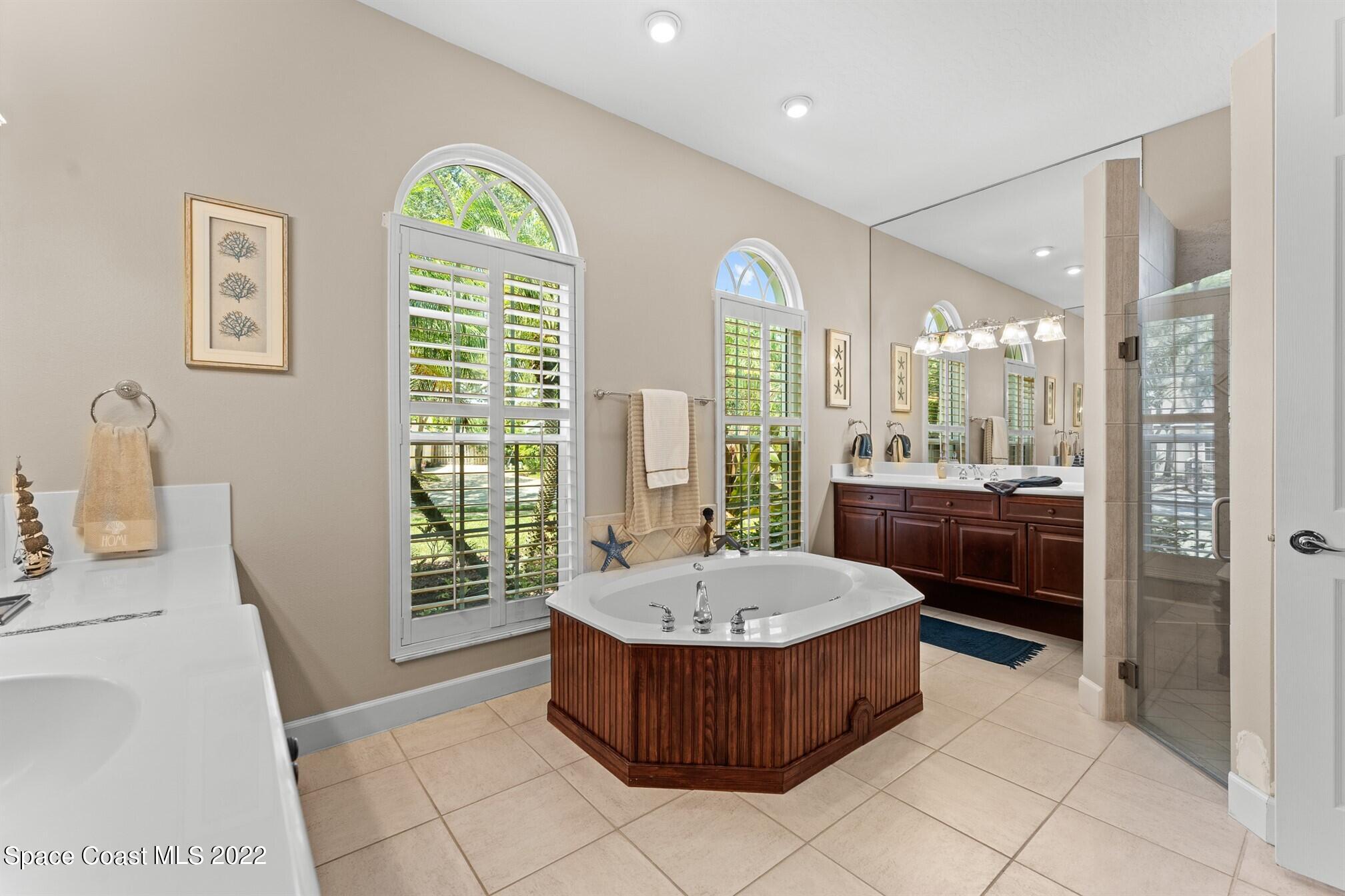 581 Nightingale Drive Indialantic, FL 32903 - Photo 26 of 67 a large spacious bathroom with a tub a double vanity sink a mirror a window and a shower