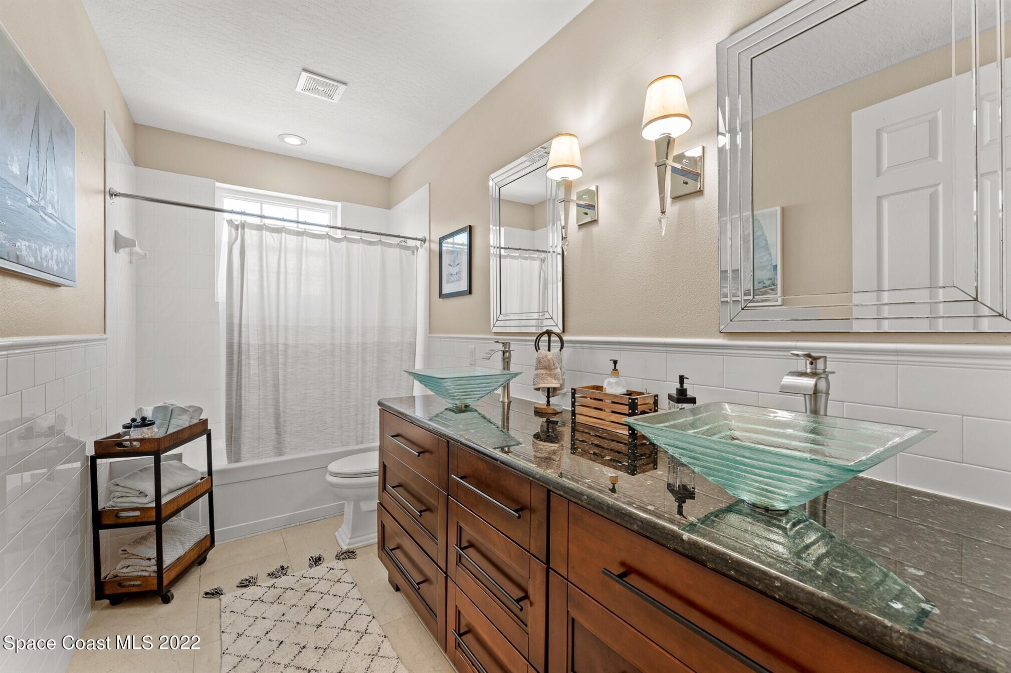 581 Nightingale Drive Indialantic, FL 32903 - Photo 38 of 67 a bathroom with a double vanity sink toilet and a mirror