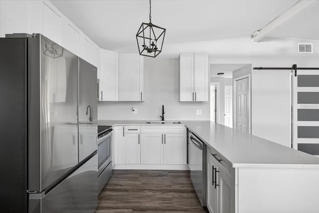 a kitchen with stainless steel appliances granite countertop a sink cabinets and wooden floor
