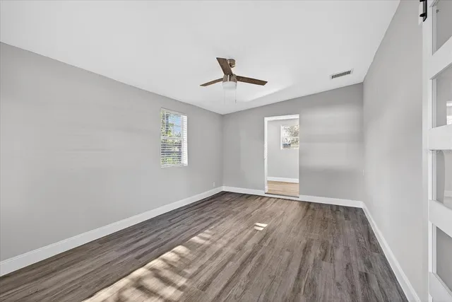 a view of an empty room with wooden floor and a window