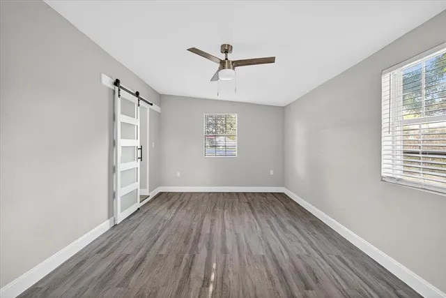 a view of empty room with wooden floor and fan