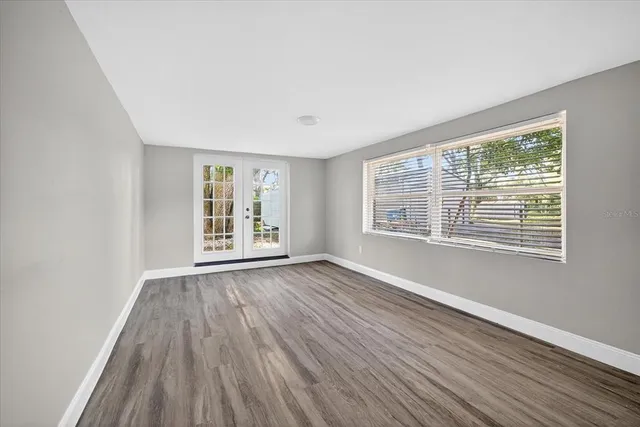 a view of an empty room with wooden floor and a window