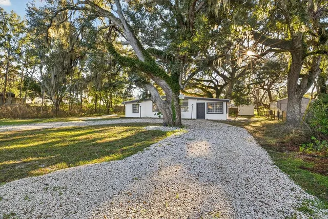 a view of a house with a big yard and large trees