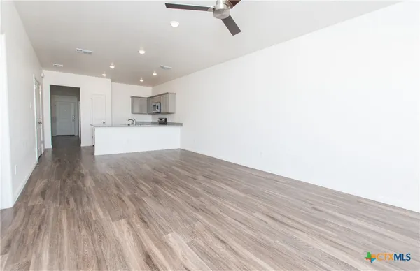 a view of a kitchen with kitchen island a sink wooden floor and stainless steel appliances