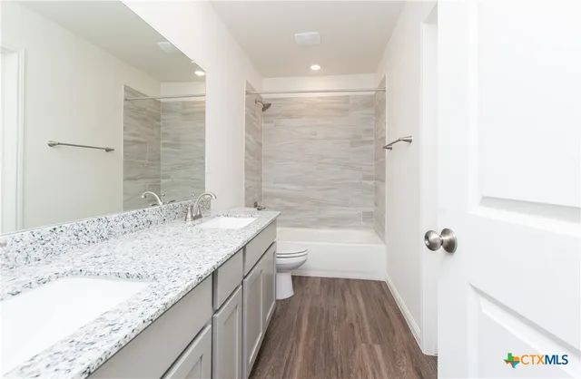 a bathroom with a granite countertop sink a toilet and shower
