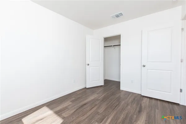a view of an empty room with wooden floor and closet
