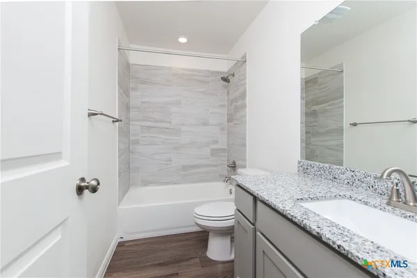 a bathroom with a granite countertop sink toilet tub and shower
