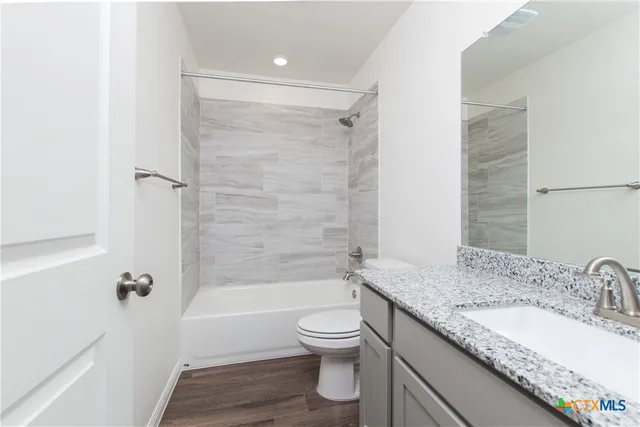 a bathroom with a granite countertop sink toilet tub and shower