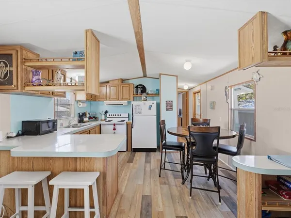a kitchen with stainless steel appliances kitchen island granite countertop a table chairs and a refrigerator