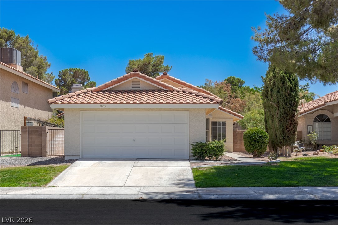 A classic tile roof and concrete driveway define this charming single-story exterior.