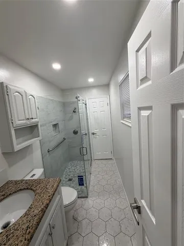 a bathroom with a granite countertop sink toilet and shower