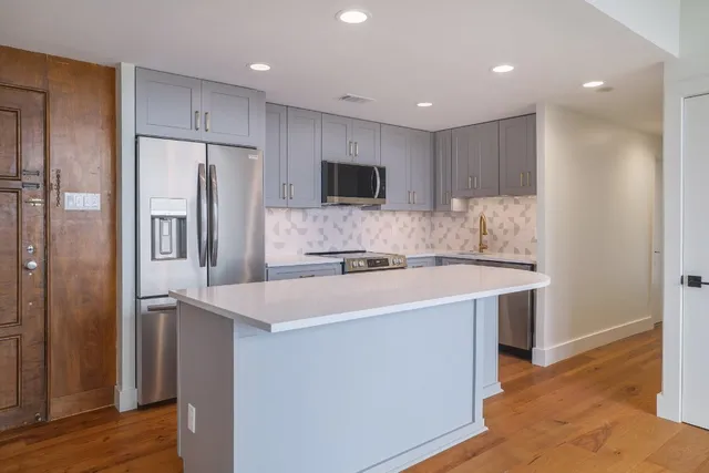 a kitchen with kitchen island a sink stainless steel appliances and refrigerator