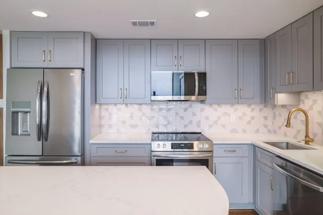 a kitchen with kitchen island a sink stainless steel appliances and cabinets