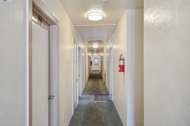 a view of a hallway with wooden floor and a bathroom