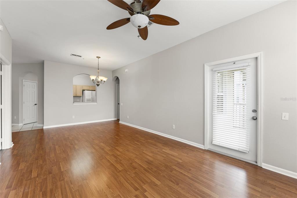 1224 South Hiawassee Road, Unit 636 Orlando, FL 32835 - Photo 9 of 43 an empty room with wooden floor chandelier fan and windows