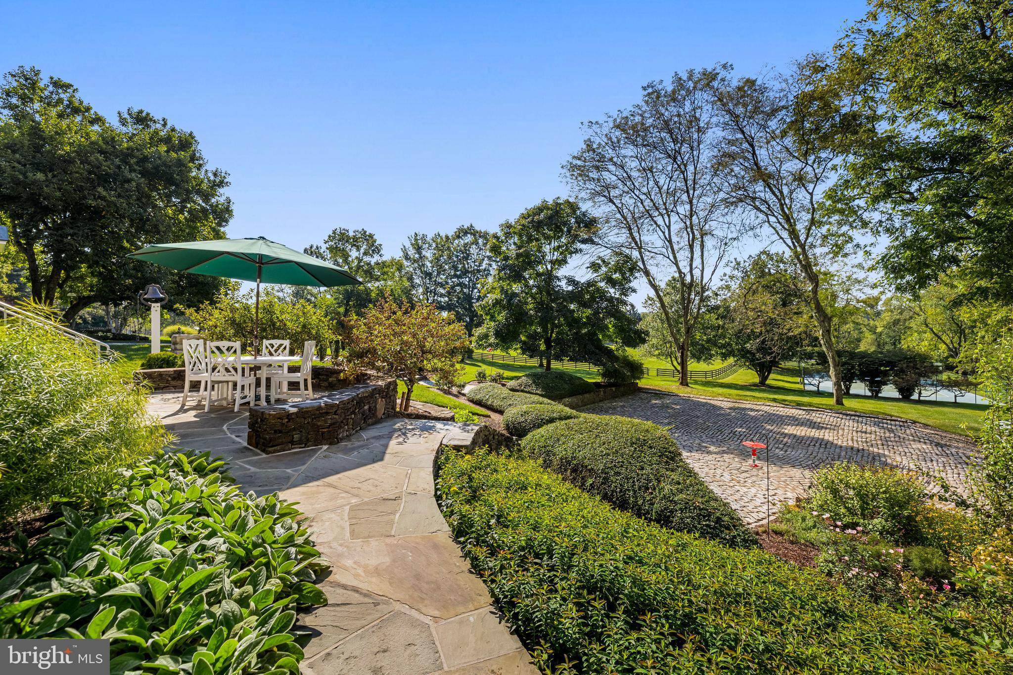 14921 Tanyard Road Sparks Glencoe, MD 21152 - Photo 58 of 150 a view of a patio with couches and table and chairs under an umbrella with large trees