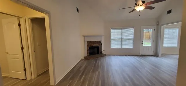 a view of a livingroom with wooden floor a ceiling fan and windows