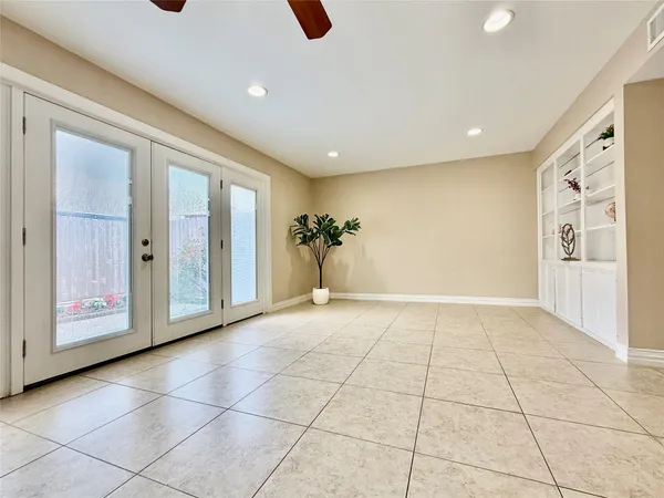 an empty room with wooden floor fan and windows