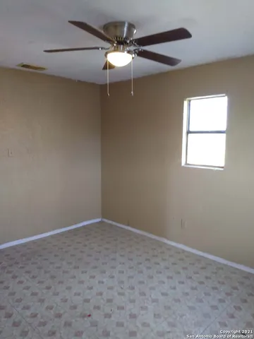 an empty room with a window and a fan