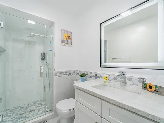 a bathroom with a granite countertop sink a toilet and shower
