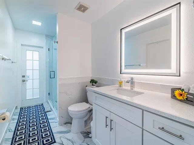 a bathroom with a sink a toilet a shower and a mirror