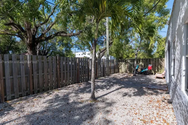 a view of a backyard with wooden fence and a large tree