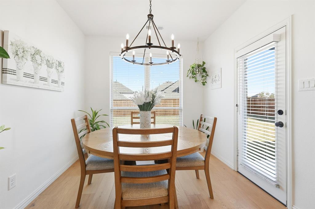4420 Minnow Cove Oak Point, TX 75068 - Photo 19 of 40 a dining room with wooden floor a chandelier a wooden table and chairs