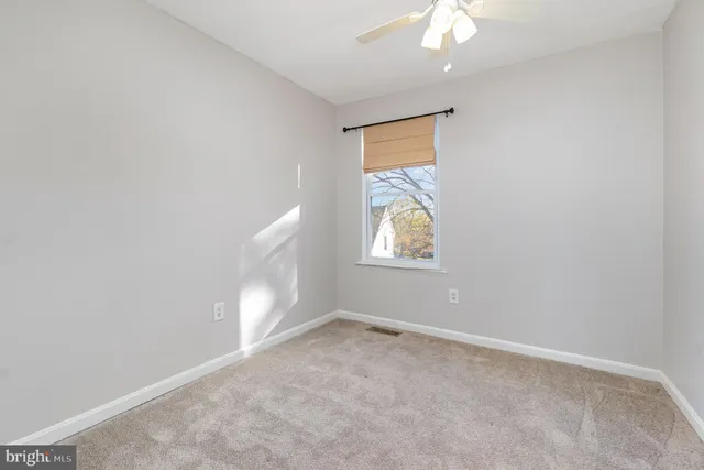 an empty room with a window and a fan