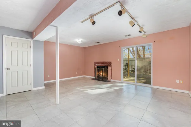 a view of an empty room with a fireplace and a window