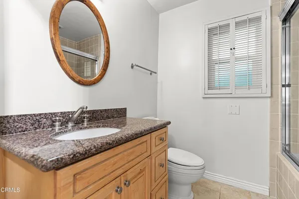 a bathroom with a granite countertop toilet a sink and a mirror