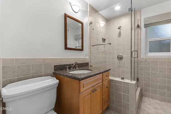 a bathroom with a granite countertop sink a toilet a mirror and shower