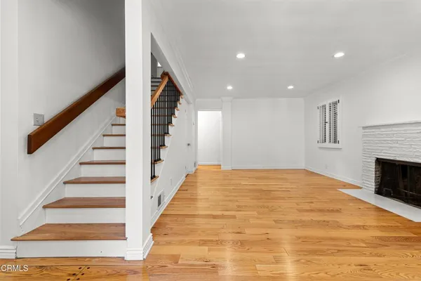 a view of an empty room with wooden floor and fireplace