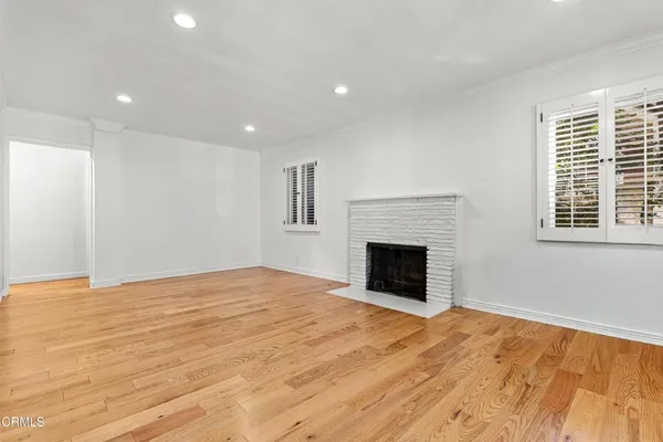 a view of empty room with wooden floor and fireplace