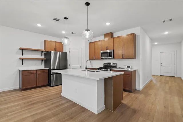 a kitchen with stainless steel appliances granite countertop a sink a stove and a refrigerator