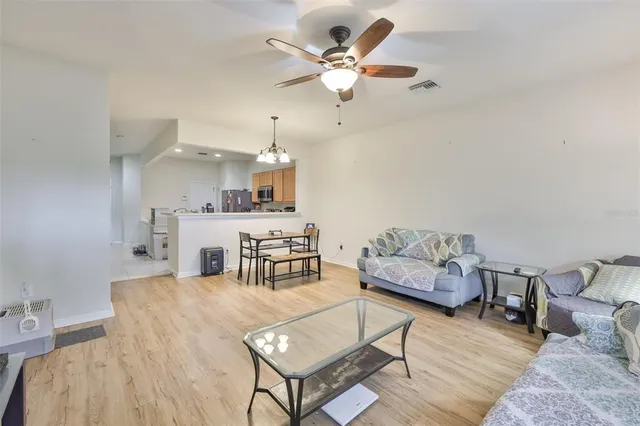 a living room with furniture kitchen view and a chandelier