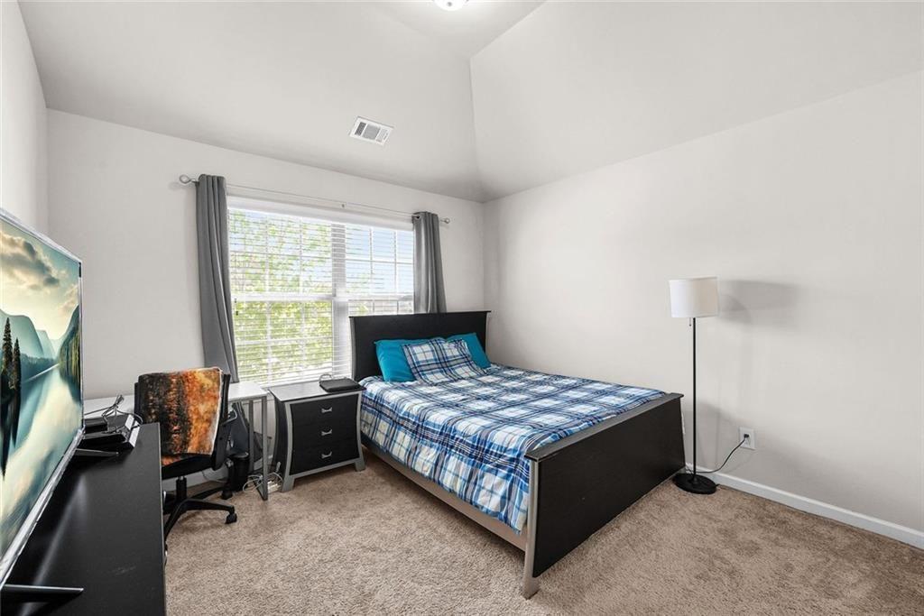 7823 Shertall Road Fairburn, GA 30213 - Photo 16 of 40 a bedroom with a bed a table and a flat screen tv