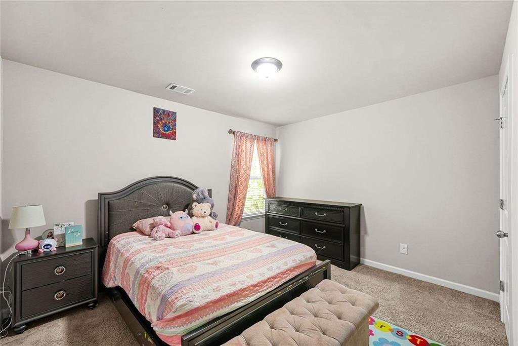 7823 Shertall Road Fairburn, GA 30213 - Photo 19 of 40 a bedroom with a bed and a lamp on dresser