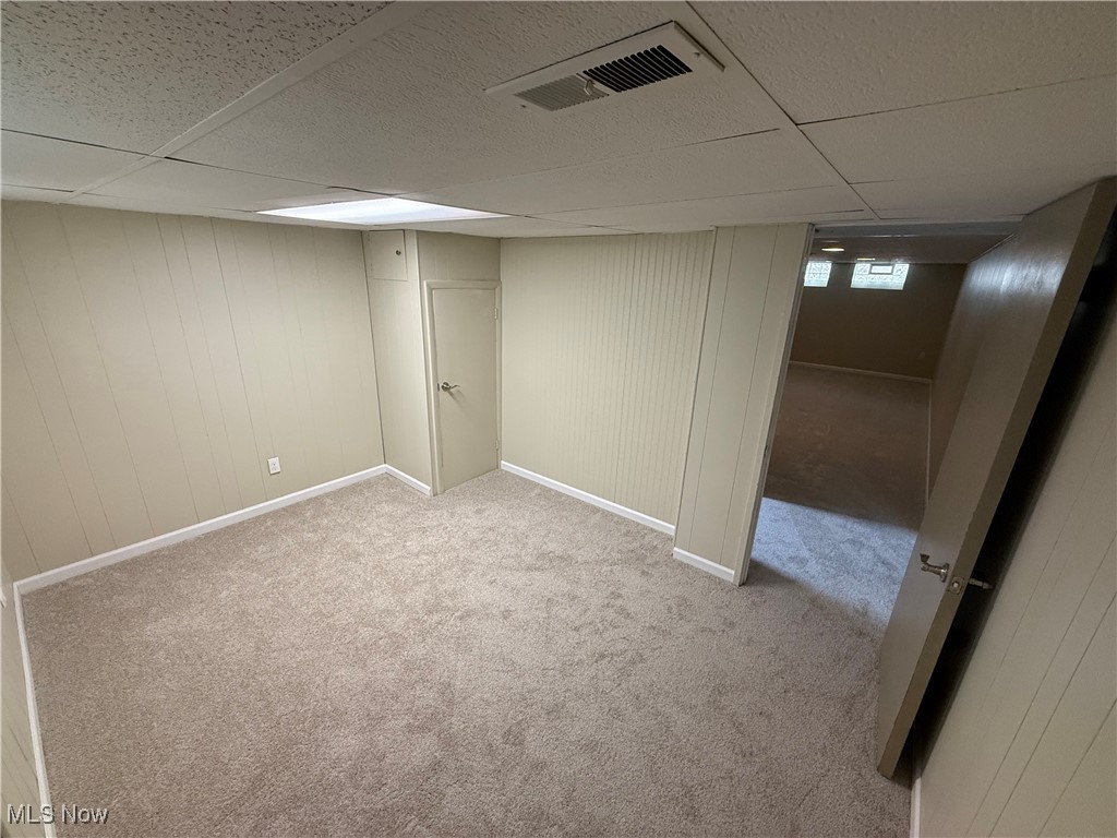 9417 Alexander Road Garfield Heights, OH 44125 - Photo 31 of 38 Below grade area with visible vents, baseboards, a drop ceiling, and carpet floors