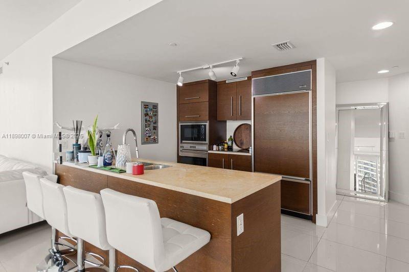 465 Brickell Avenue, Unit 1602 Miami, FL 33131 - Photo 8 of 30 a kitchen with a table chairs refrigerator and microwave