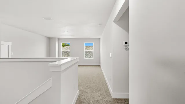 a view of hallway with window and wooden floor
