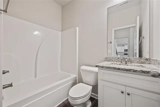 a bathroom with a granite countertop toilet a sink and a bathtub
