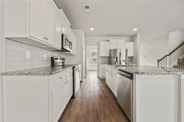 a kitchen with granite countertop a sink a stove top oven a counter space and cabinets