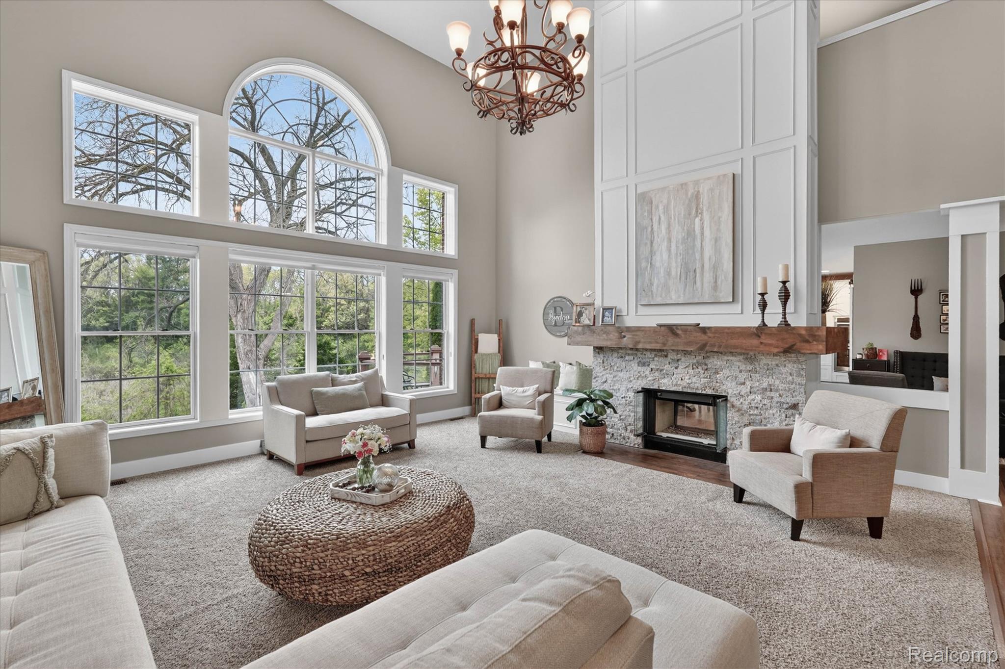 9074 Ridgefield Drive Brighton, MI 48114 - Photo 7 of 75 Living room with a high ceiling, a chandelier, carpet flooring, and a stone fireplace
