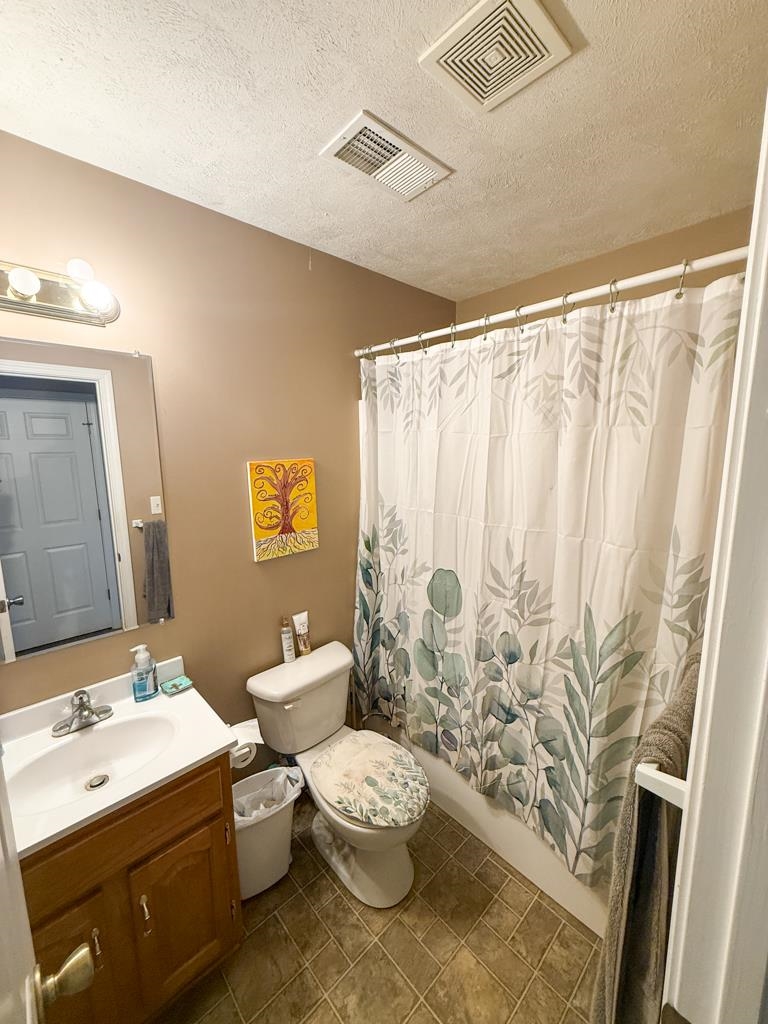 0 Poplar Grove Cemetery Road Henning, TN 38041 - Photo 13 of 40 Bathroom featuring a single-sink vanity with wood-finish cabinetry, a toilet, and a shower/tub combination with a white curtain