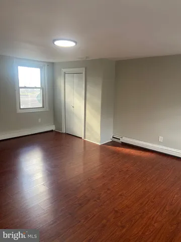 an empty room with wooden floor and windows with curtains